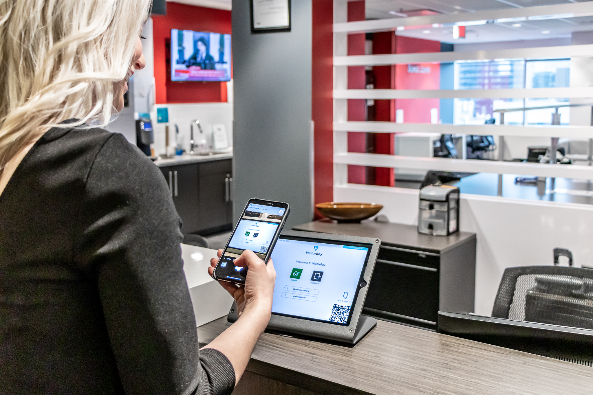 Visitor using VisitorBay QR code and iPad visitor sign-in at reception